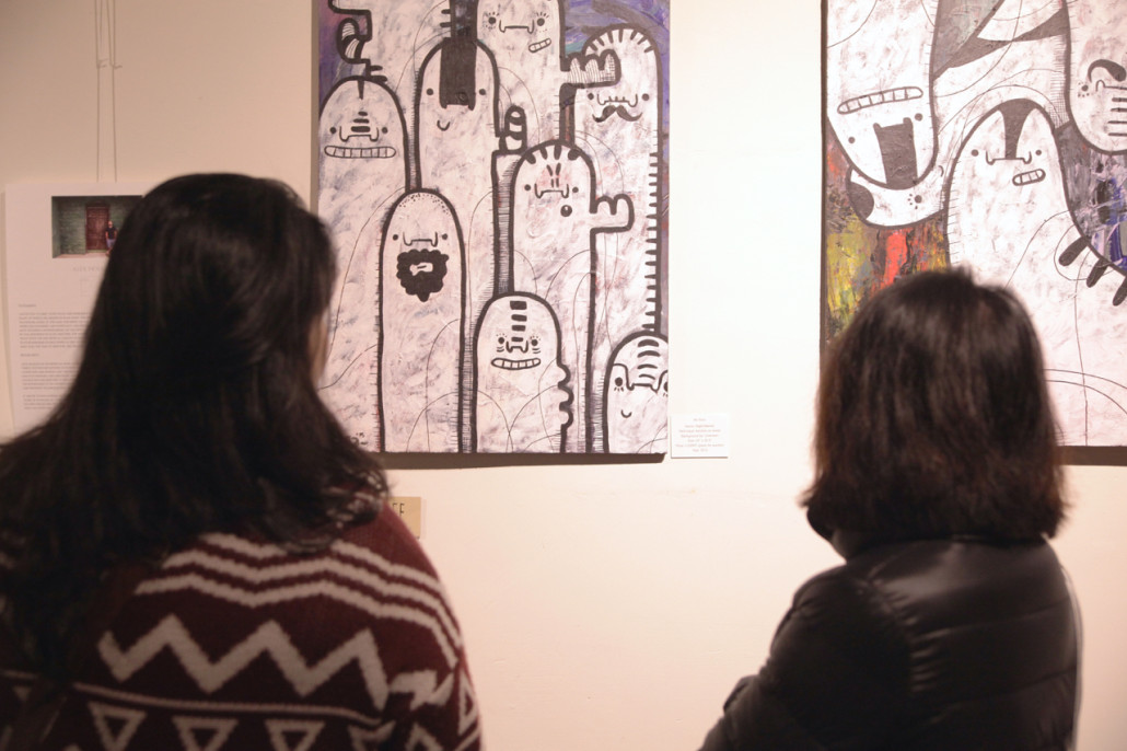 Two attendees pause to take in a view of Bara's artwork at the opening night of Visual Dialogues 3. 